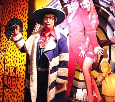 Austin Powers in a wide-brimmed hat on a colourful stage