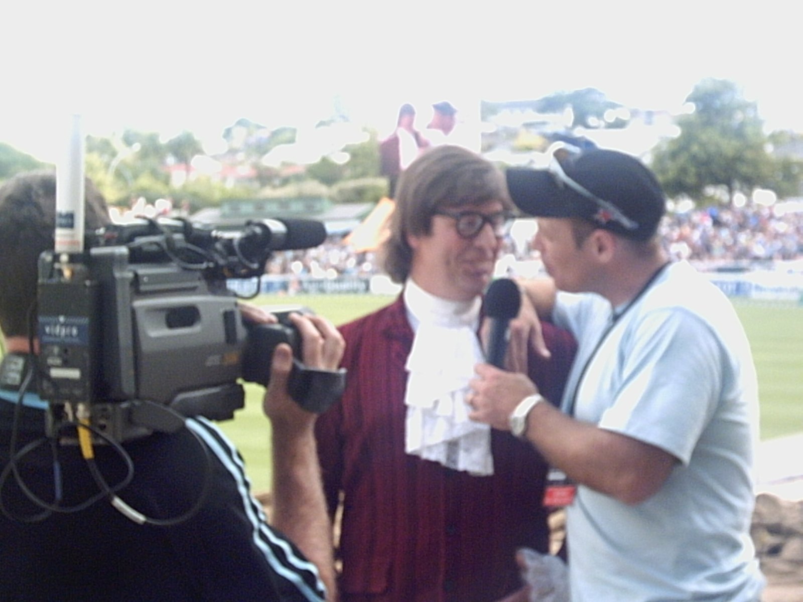 Austin Powers being interviewed on camera at a cricket ground