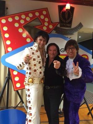 Elvis, Austin Powers and another tribute act posing by a lit stage sign