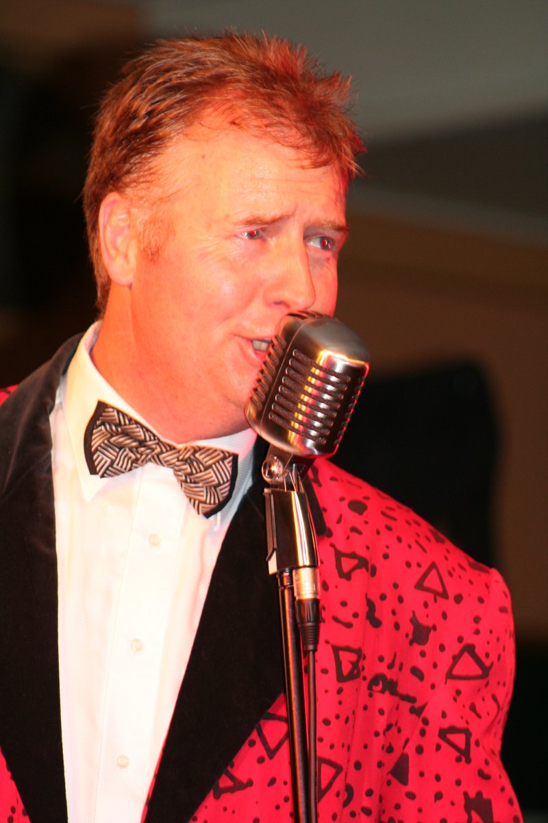 Gary Brown in a red sequin jacket singing into a vintage microphone