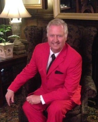 Gary Brown seated in a red suit and bow tie