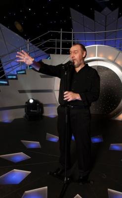 Male vocalist in a black suit on stage