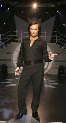 Crooner in a black suit performing on a lit stage