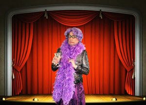 Dame Edna tribute artist in a lilac gown in front of red curtains