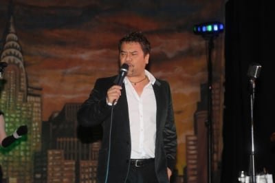 Singer in a white shirt performing under stage lights